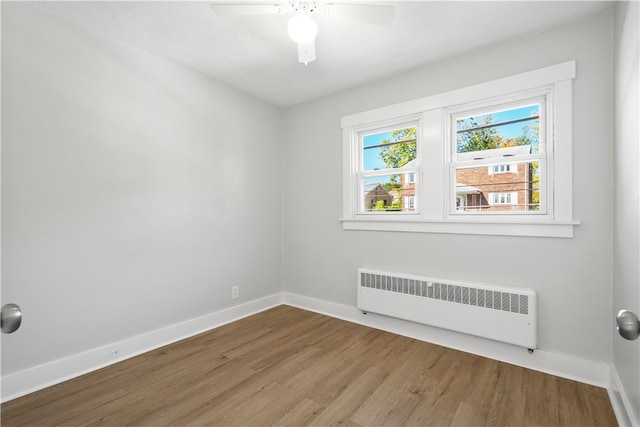 spare room with radiator heating unit, hardwood / wood-style flooring, and ceiling fan