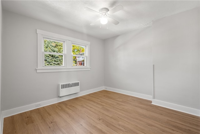 empty room featuring radiator, ceiling fan, and light wood-type flooring