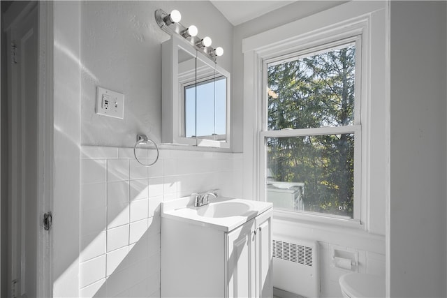 bathroom featuring tile walls, vanity, toilet, and radiator