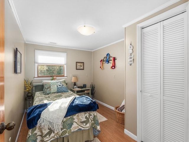 bedroom featuring crown molding, light hardwood / wood-style flooring, and a closet