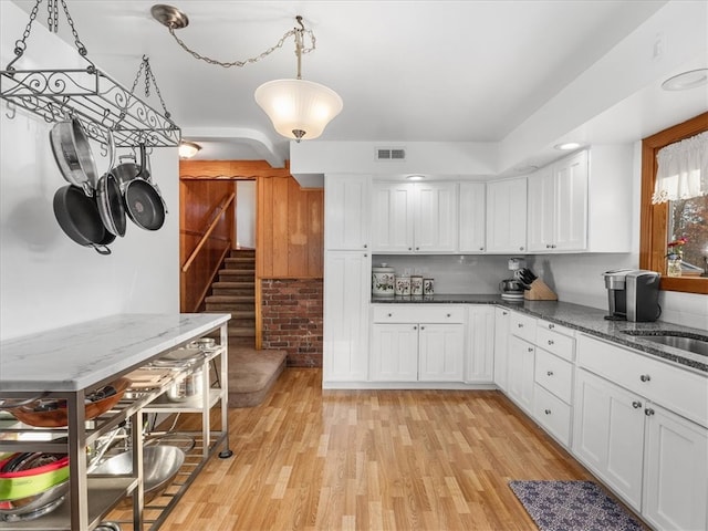 kitchen featuring white cabinetry, hanging light fixtures, and light wood-type flooring