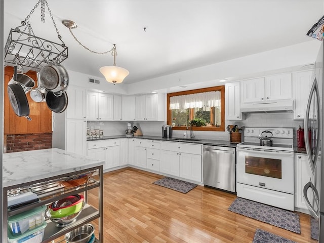 kitchen featuring white cabinets, appliances with stainless steel finishes, light wood-type flooring, pendant lighting, and sink