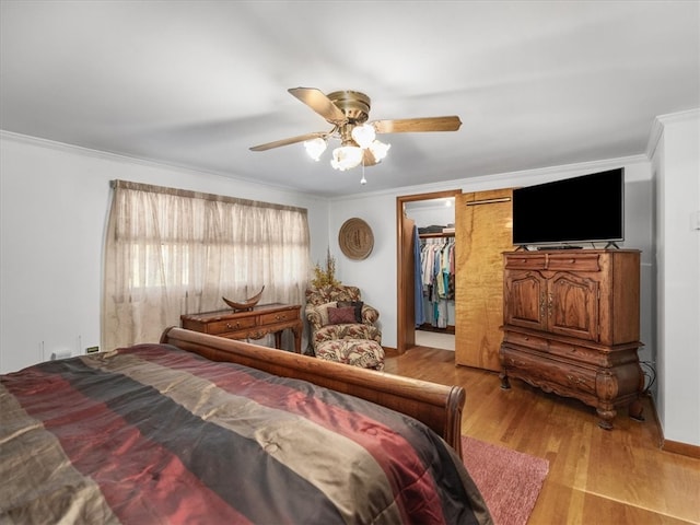 bedroom featuring a spacious closet, a closet, ceiling fan, light hardwood / wood-style floors, and ornamental molding