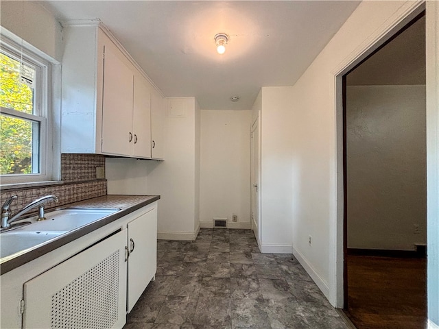 kitchen with sink, white cabinetry, and backsplash