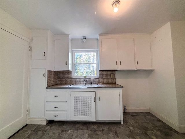 kitchen featuring sink, white cabinetry, and backsplash