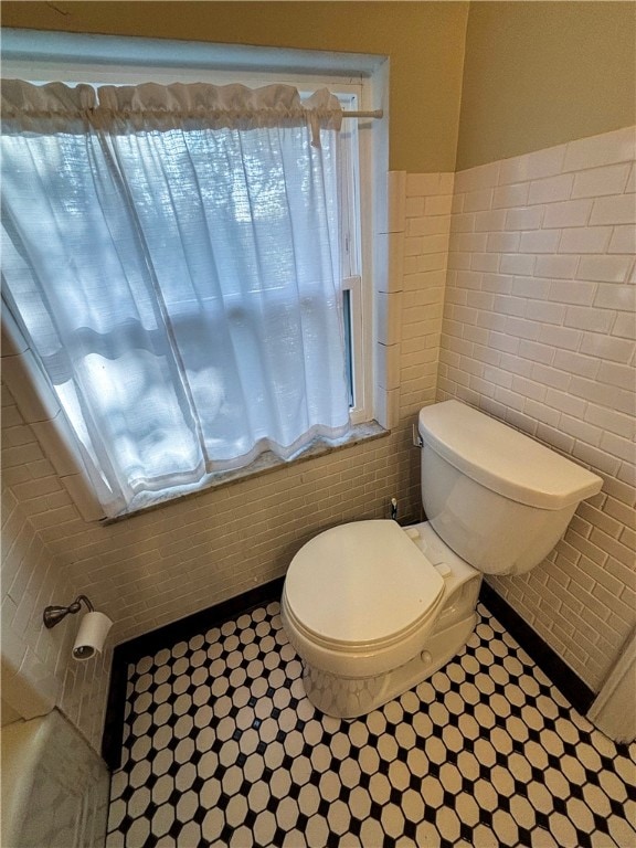 bathroom featuring toilet and tile walls