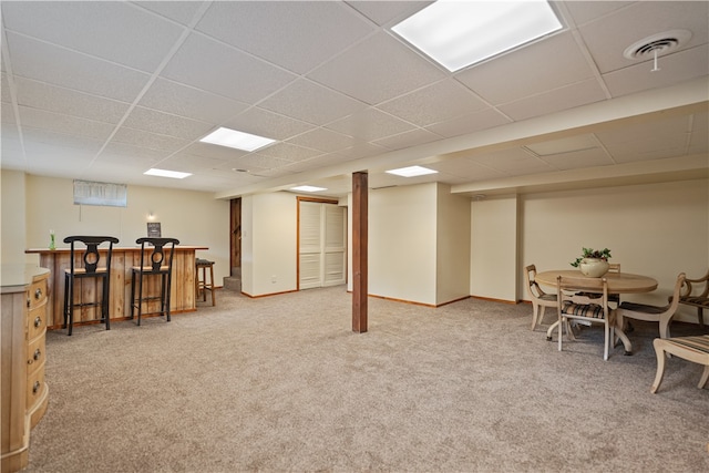 basement with light carpet, indoor bar, and a paneled ceiling