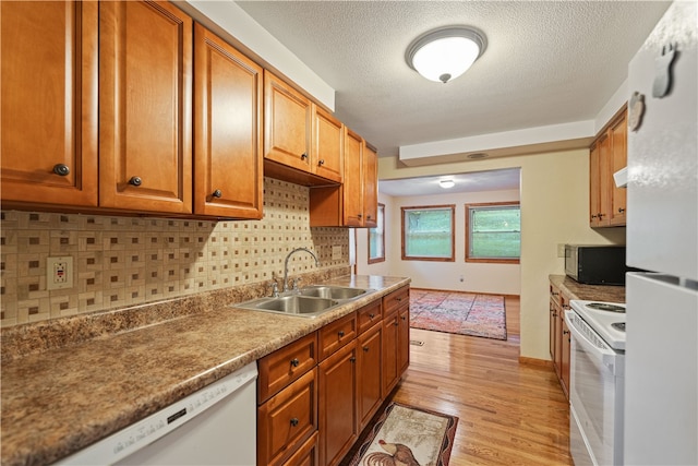 kitchen featuring white appliances, sink, a textured ceiling, light hardwood / wood-style floors, and decorative backsplash