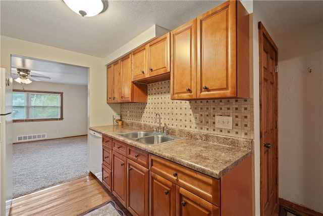 kitchen featuring tasteful backsplash, a textured ceiling, light hardwood / wood-style flooring, sink, and white appliances