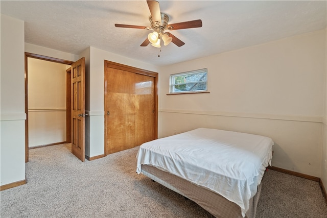 bedroom with a closet, a textured ceiling, light colored carpet, and ceiling fan