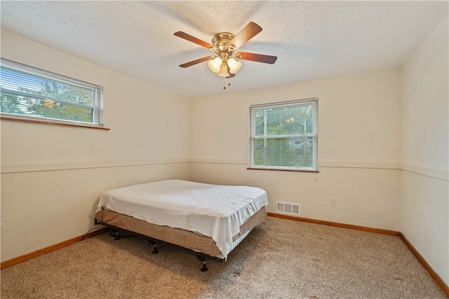 carpeted bedroom featuring a textured ceiling and ceiling fan