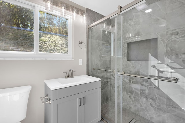 bathroom with vanity, toilet, and a shower with door