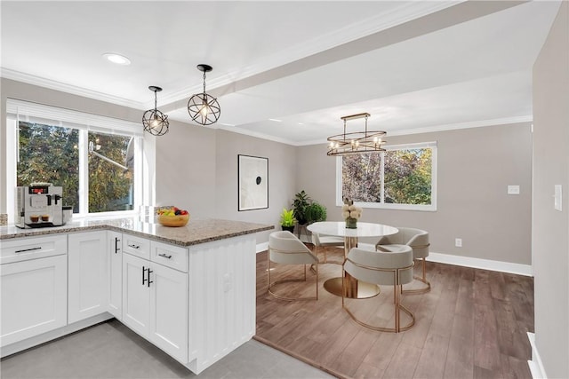 kitchen featuring a notable chandelier, light stone counters, white cabinets, crown molding, and baseboards