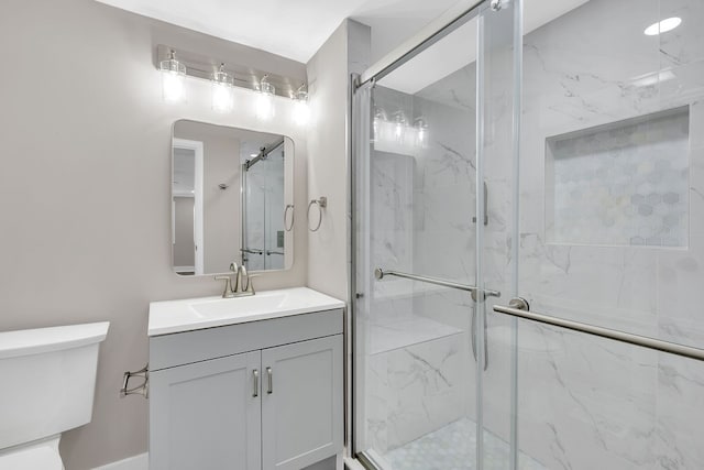 bathroom featuring vanity, a shower with shower door, and toilet