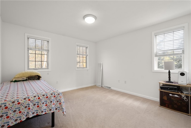 bedroom with light carpet and multiple windows