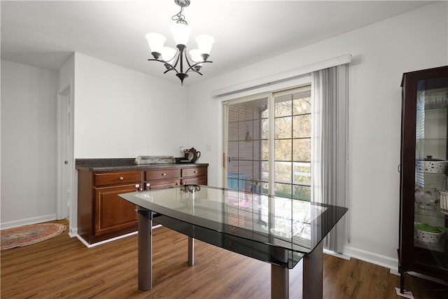 dining room with dark wood-type flooring and a notable chandelier