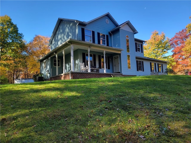 rear view of property featuring a porch and a lawn