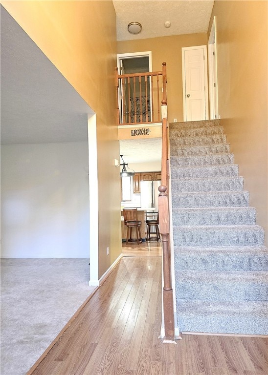 stairs featuring a textured ceiling and hardwood / wood-style flooring