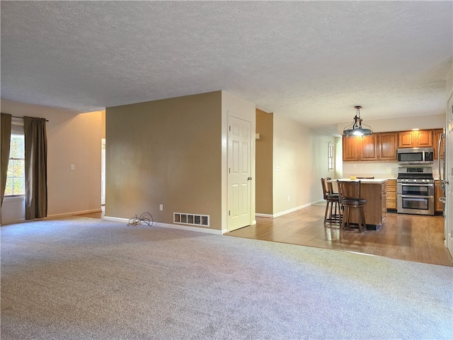 unfurnished living room with light hardwood / wood-style floors and a textured ceiling