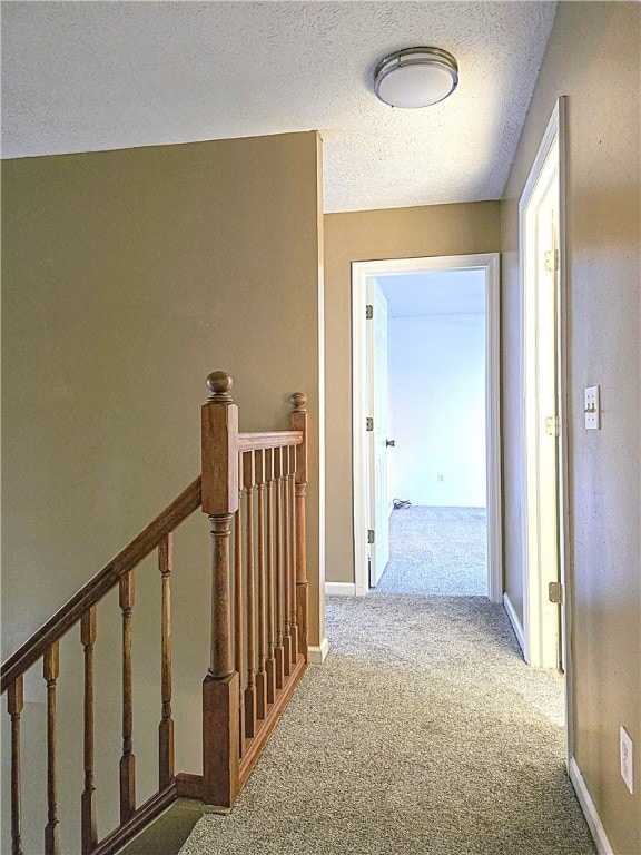 hallway with a textured ceiling and carpet floors