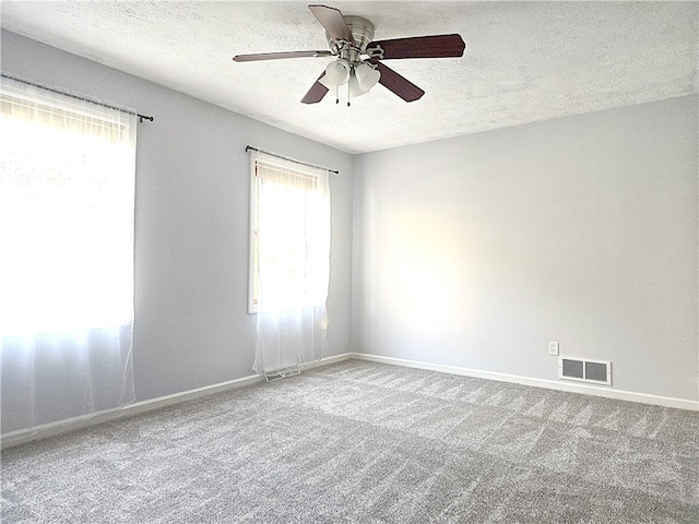 carpeted empty room with ceiling fan and a textured ceiling