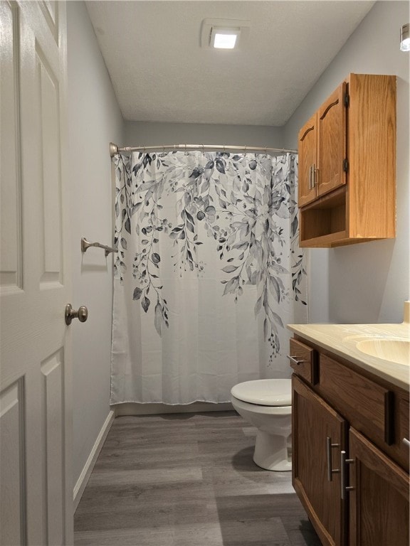 bathroom featuring vanity, toilet, hardwood / wood-style flooring, and walk in shower