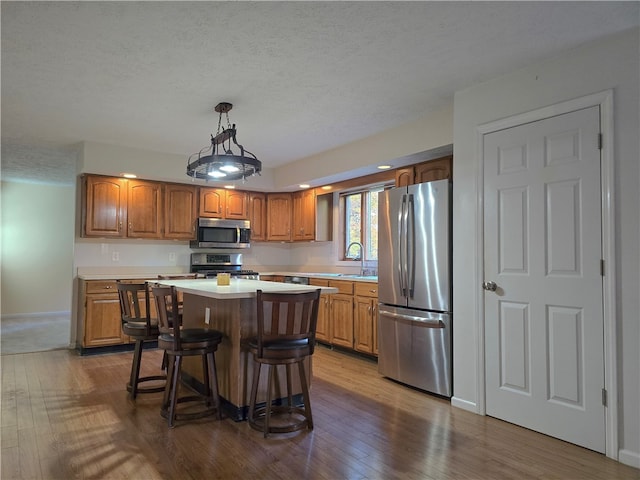 kitchen with a breakfast bar, hardwood / wood-style floors, stainless steel appliances, and a kitchen island