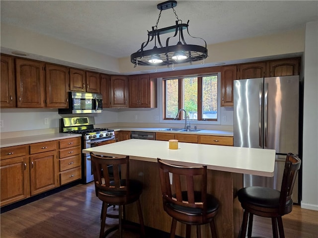 kitchen with stainless steel appliances, sink, a center island, a textured ceiling, and dark hardwood / wood-style flooring