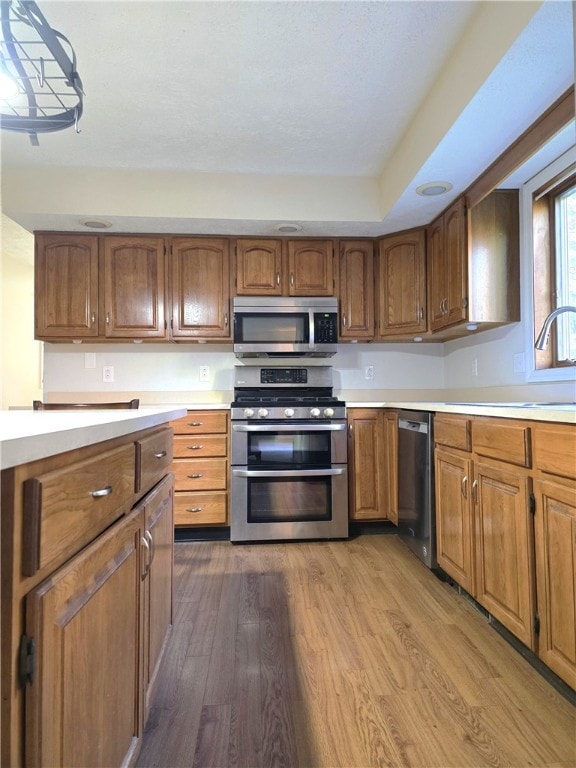 kitchen with sink, stainless steel appliances, and light hardwood / wood-style floors