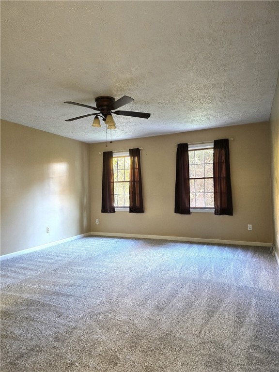 carpeted spare room featuring ceiling fan, a textured ceiling, and plenty of natural light