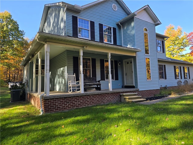 view of front of home with a front yard, central air condition unit, and a porch