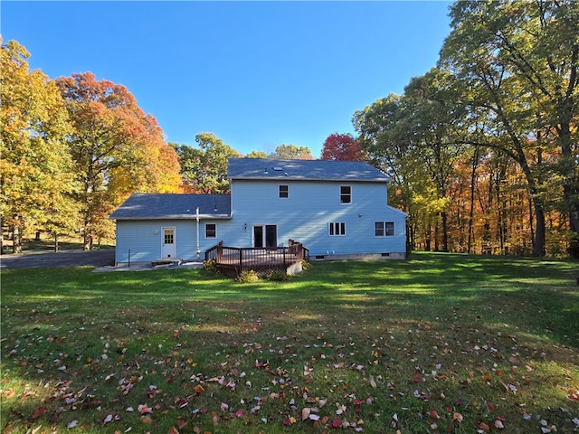 rear view of property featuring a wooden deck and a lawn