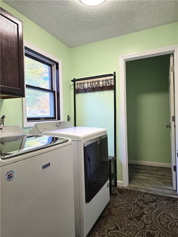 clothes washing area featuring dark wood-type flooring, a textured ceiling, cabinets, and washing machine and clothes dryer