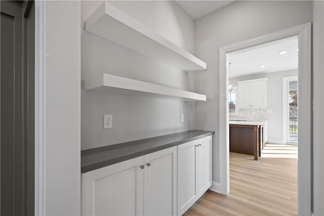 bar featuring white cabinetry, backsplash, and light hardwood / wood-style flooring