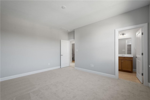 unfurnished bedroom featuring ensuite bathroom, sink, and light carpet