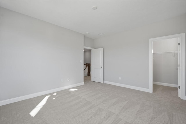 unfurnished bedroom featuring light colored carpet, a walk in closet, and a closet