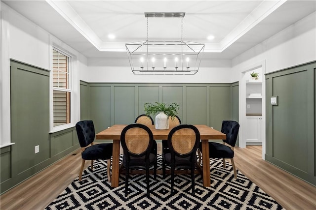 dining room featuring a tray ceiling, an inviting chandelier, and light hardwood / wood-style floors