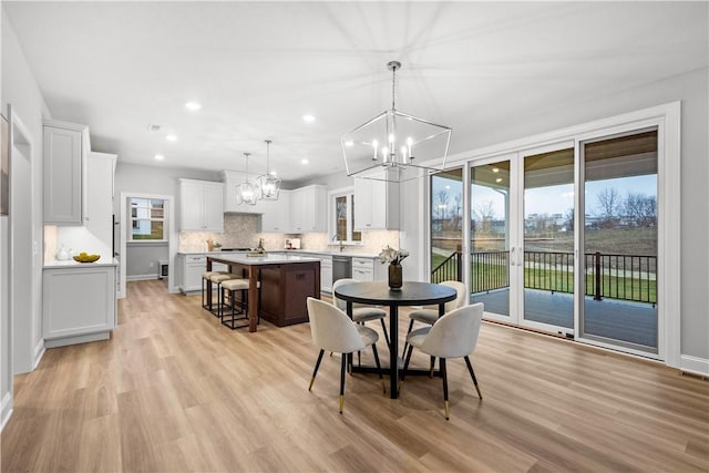 dining space with light hardwood / wood-style floors, sink, a wealth of natural light, and a chandelier