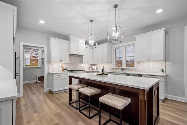 kitchen with white cabinets, decorative light fixtures, sink, and a breakfast bar area