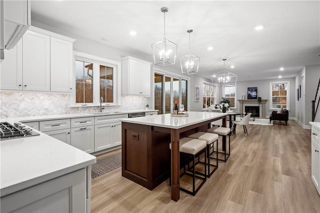 kitchen featuring sink, a center island, white cabinetry, hanging light fixtures, and black stovetop