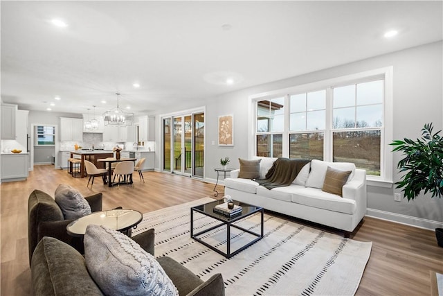 living room with light hardwood / wood-style floors and an inviting chandelier