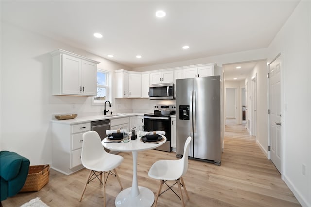 kitchen featuring white cabinetry, appliances with stainless steel finishes, light hardwood / wood-style flooring, and sink