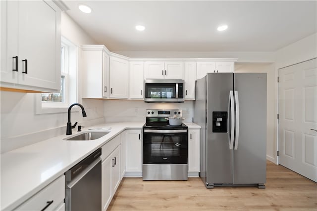 kitchen with light hardwood / wood-style flooring, stainless steel appliances, sink, and white cabinets