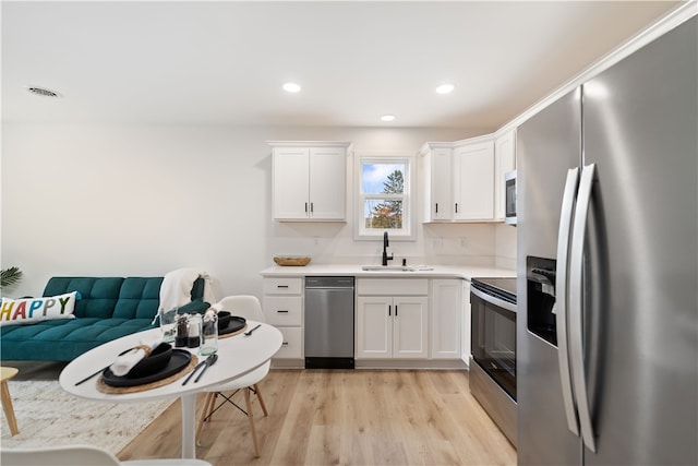 kitchen featuring sink, appliances with stainless steel finishes, white cabinets, and light hardwood / wood-style floors