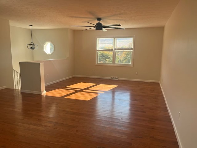 spare room featuring a textured ceiling, dark hardwood / wood-style floors, and ceiling fan with notable chandelier