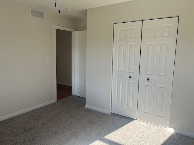 unfurnished bedroom featuring a closet and dark carpet