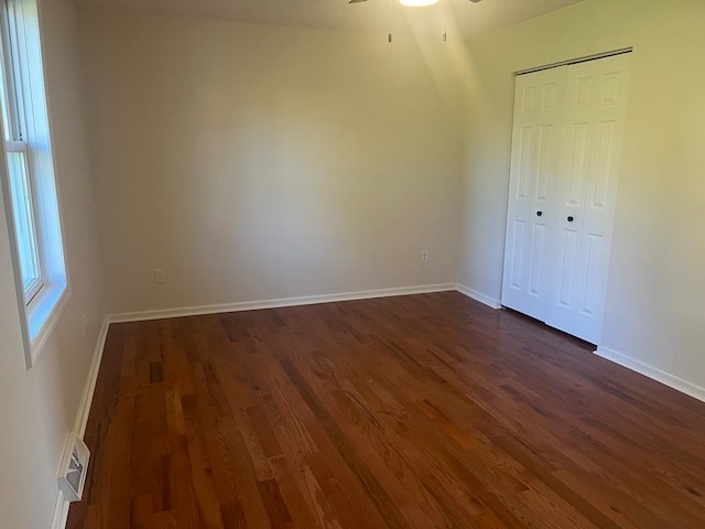 unfurnished bedroom with a closet, dark wood-type flooring, and ceiling fan