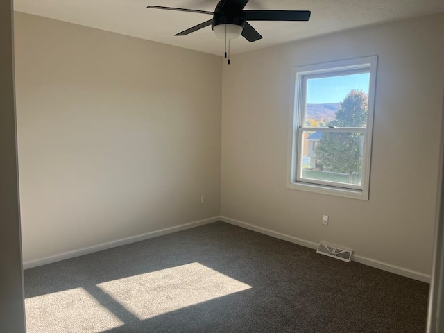 empty room featuring dark carpet and ceiling fan