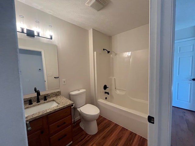 full bathroom featuring a textured ceiling, hardwood / wood-style flooring, toilet, vanity, and shower / bath combination