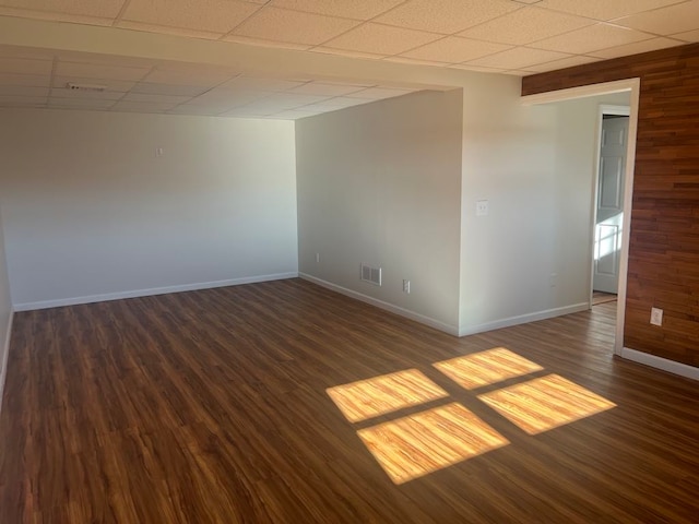 spare room featuring a paneled ceiling, wooden walls, and dark hardwood / wood-style floors